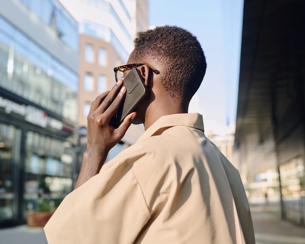 A person walking through the city while taking a call on their phone